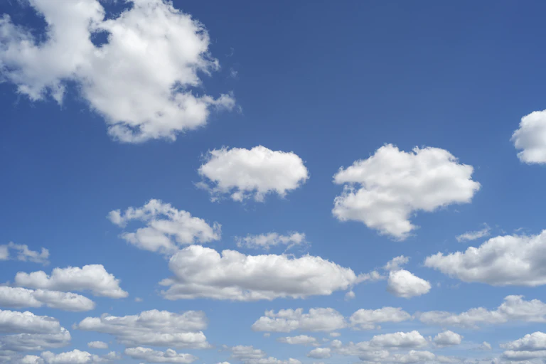 Blue sky with white puffy clouds on a bright sunny day.