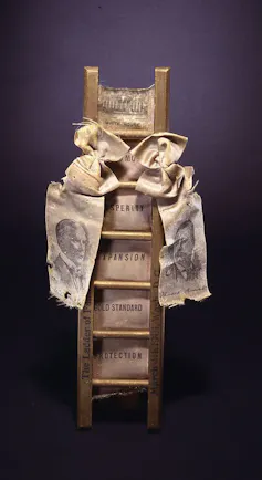 A miniature ladder with a ribbon that features the likenesses of President William McKinley and his new vice president, Theodore Roosevelt.