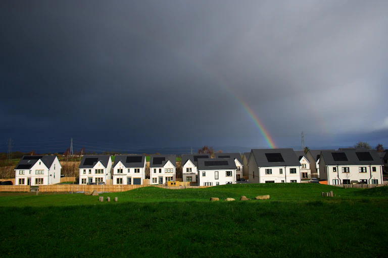 Dark sky with hint of rainbow over housing development.