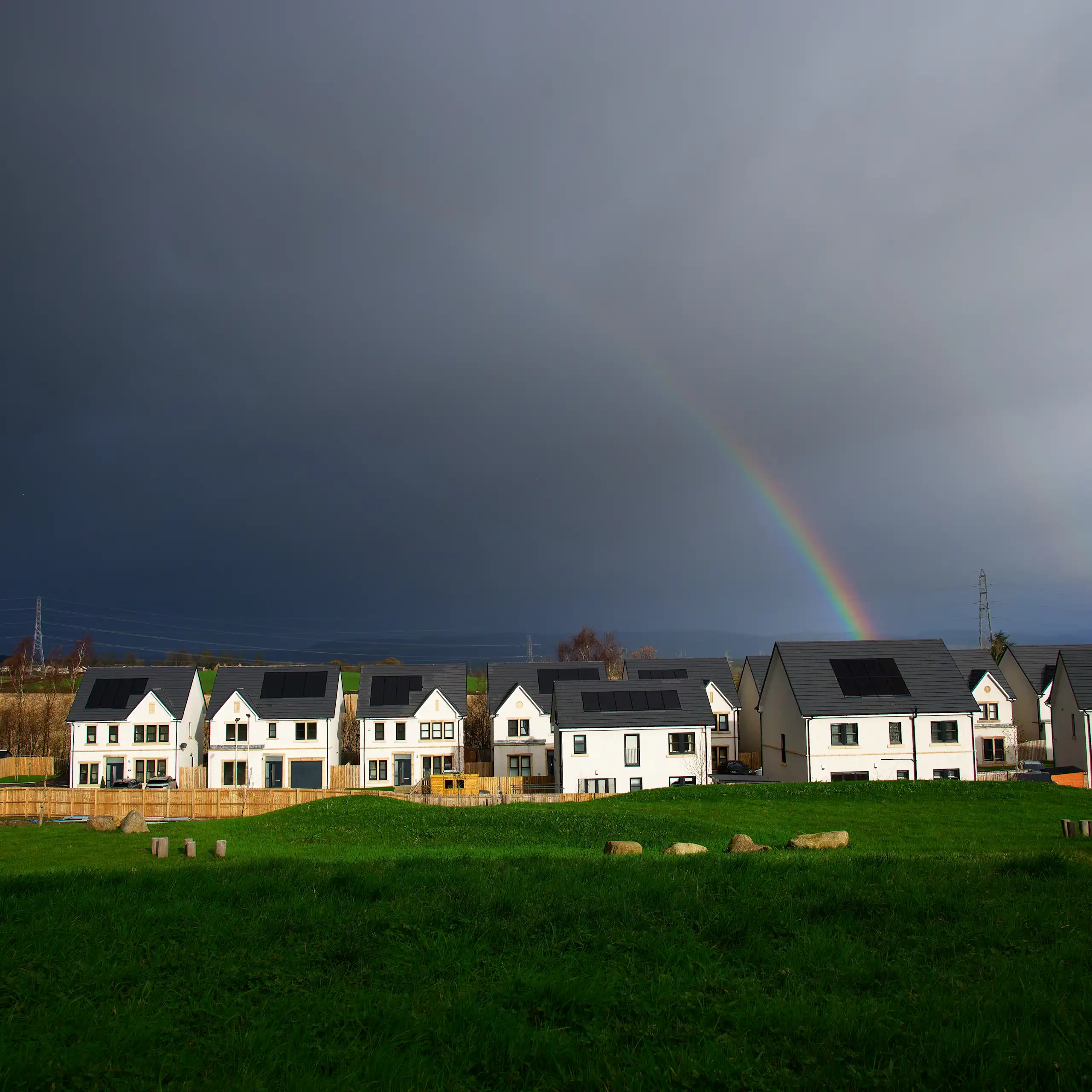 Dark sky with hint of rainbow over housing development.