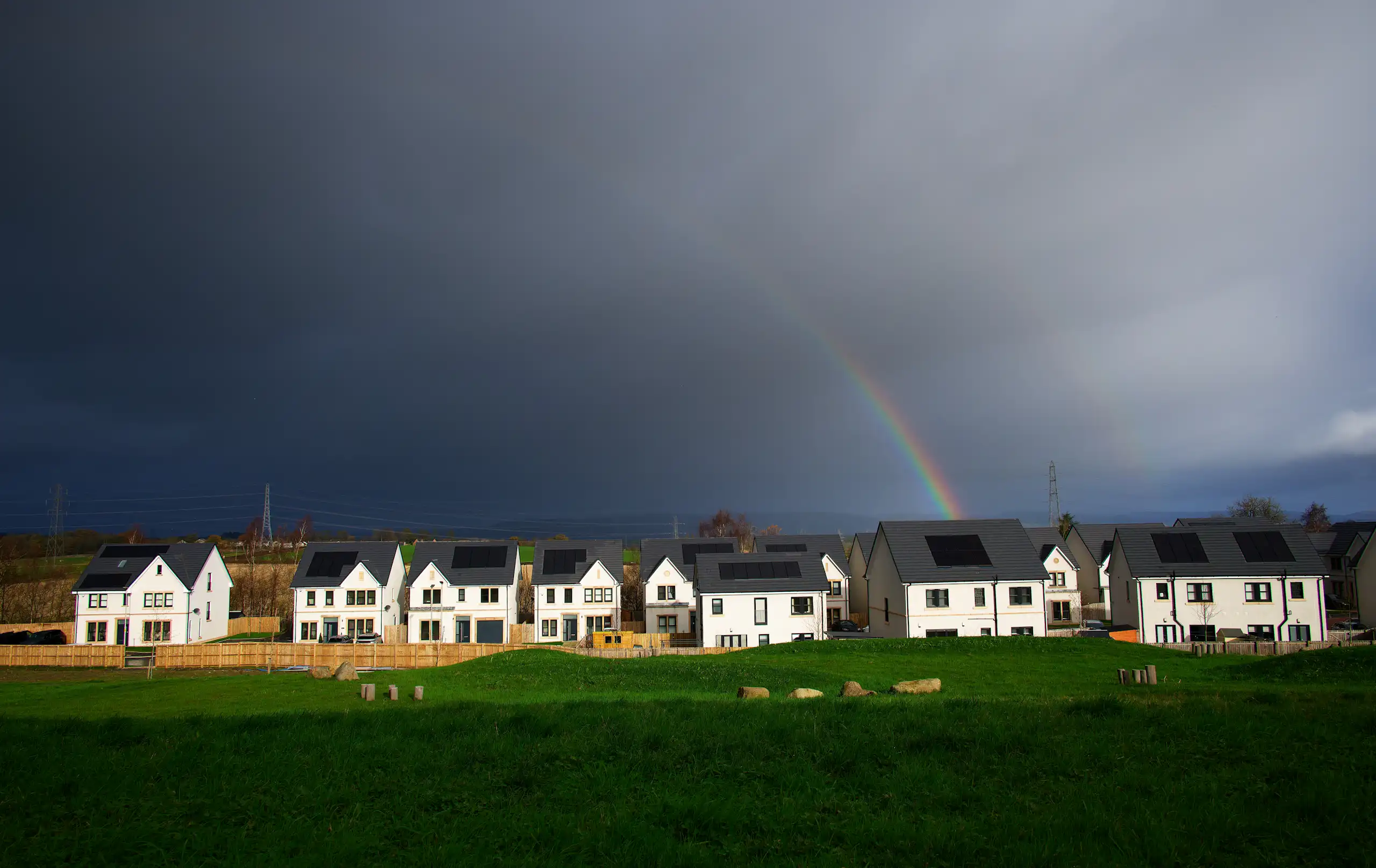 Dark sky with hint of rainbow over housing development.