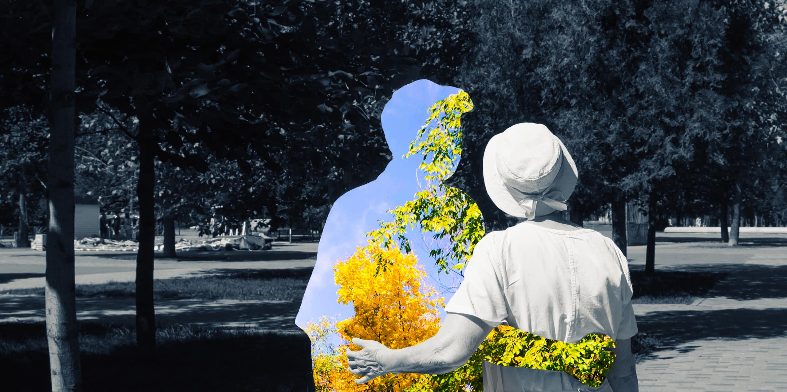 a couple from the back walking in a park, the woman and background in black and white, the man a silhouette enclsoing a color view of trees and sky