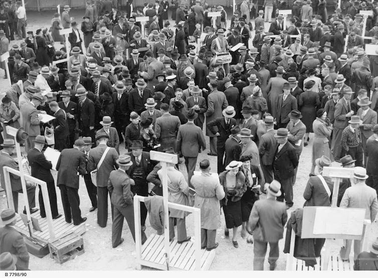 A black and white shot of a large crowd of men in suits.