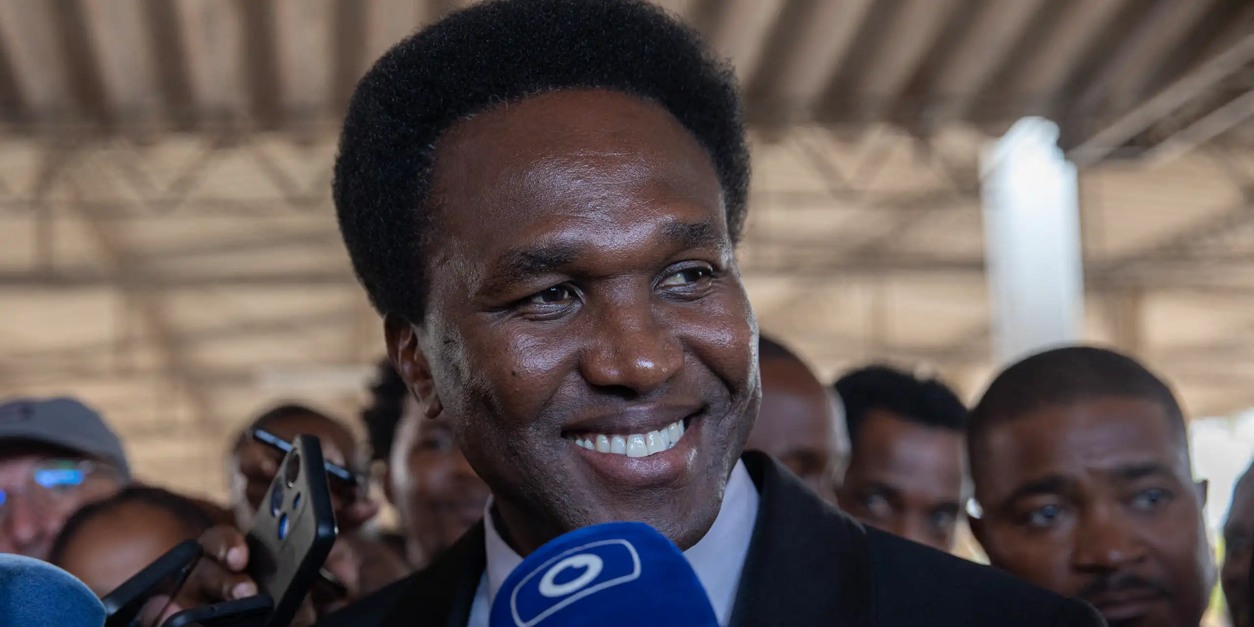 Smiling man with microphones pointed at him