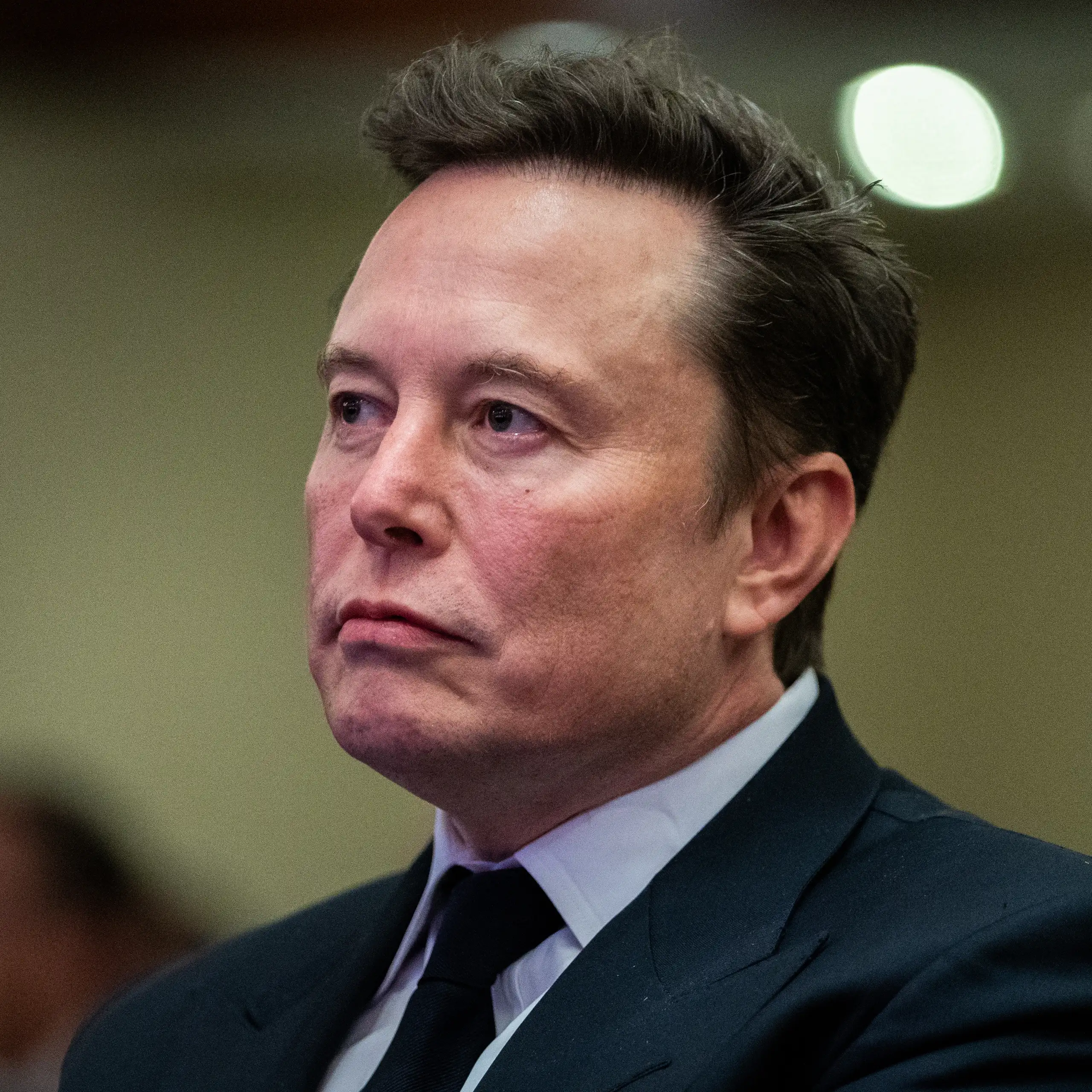 Elon Musk wearing a suit and a frown