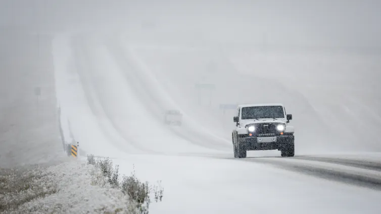 A truck drives down a snowy road.