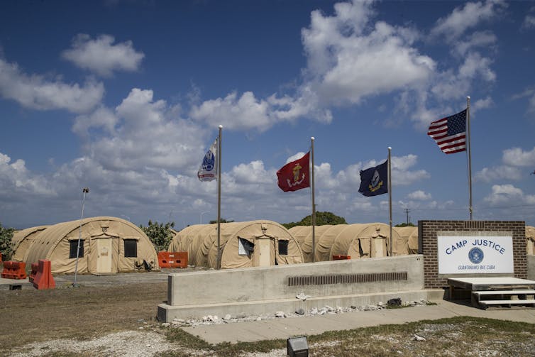 Army buildings under a sunny sky with the American flag flying.
