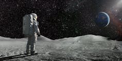A lone astronaut standing facing away from the camera dressed in full space suit with backpack, stands still looking towards a distant planet Earth. The sun illuminates a side of Earth and hundreds of stars are visible in deep space.