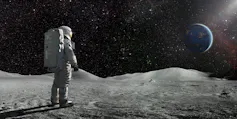 A lone astronaut standing facing away from the camera dressed in full space suit with backpack, stands still looking towards a distant planet Earth. The sun illuminates a side of Earth and hundreds of stars are visible in deep space.