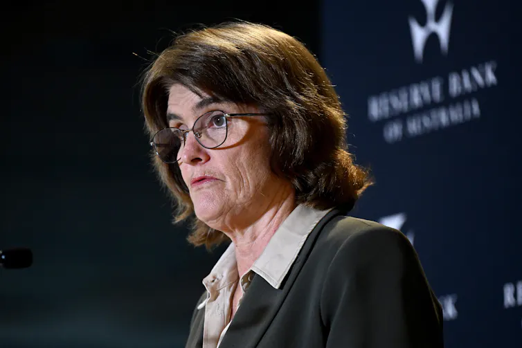 A woman in glasses speaks to the media