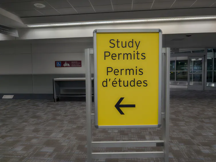 A yellow sign with black lettering that reads: study permits in english and french