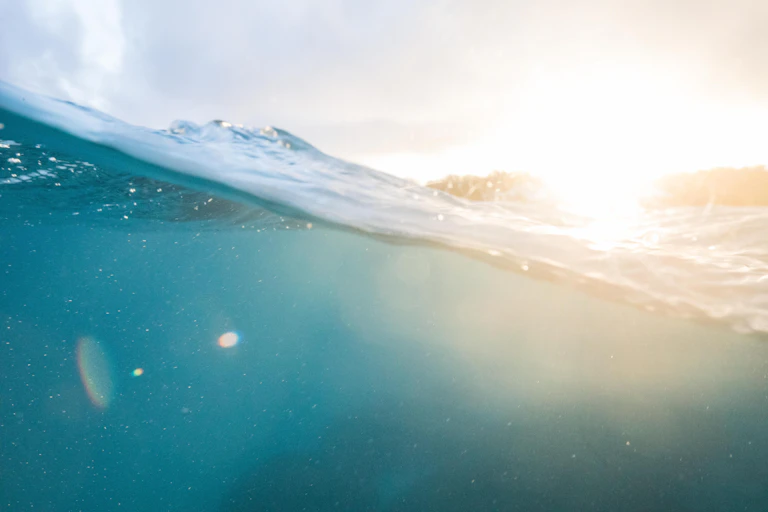 A partial underwater view of the ocean, with islands in the background