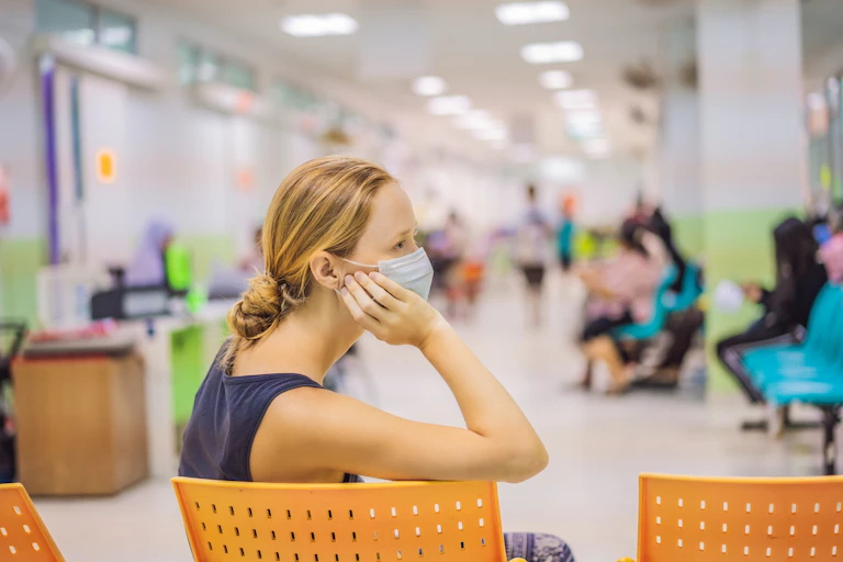 A woman wearing a mask in a medical waiting room.