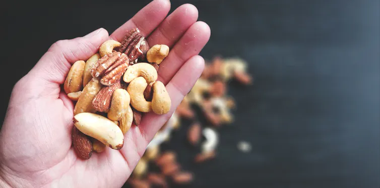 Handful of natural nuts with other nuts on a dark background