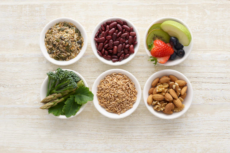 Six small bowls of high-fibre foods, including nuts and pulses.