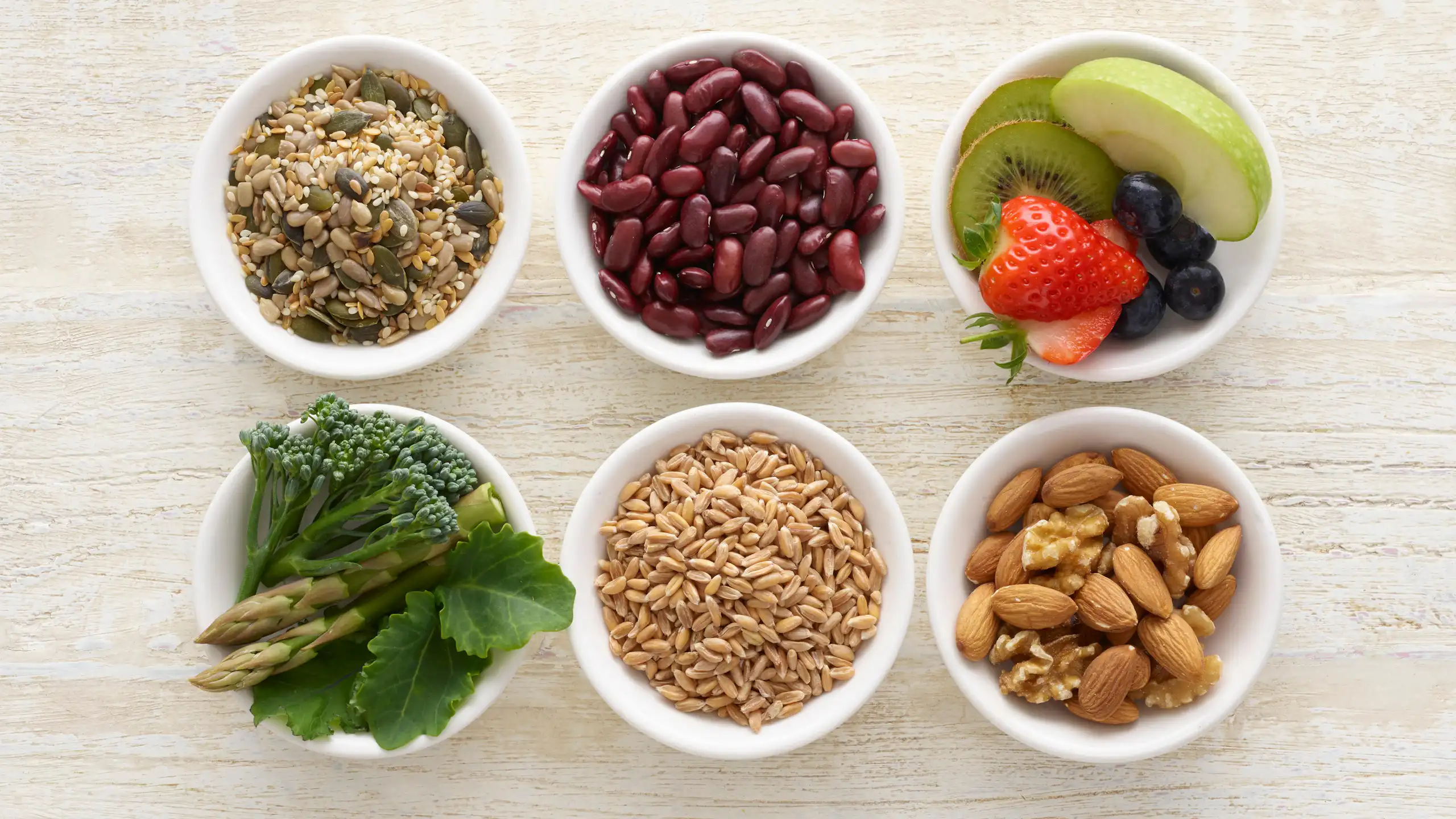 Six small bowls of high-fibre foods, including nuts and pulses.