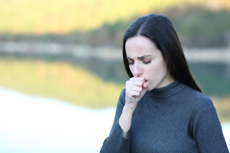 A woman coughing into her hand.