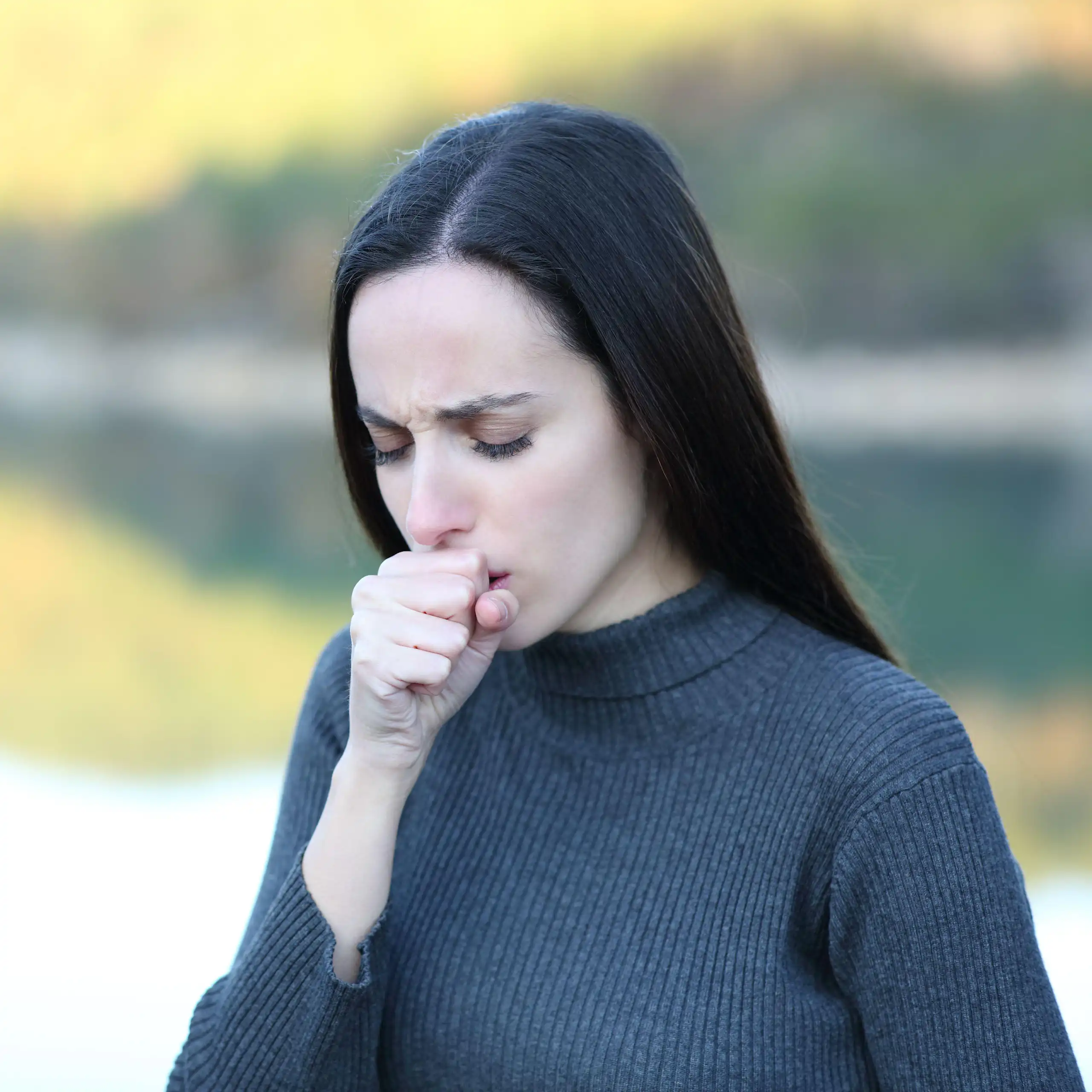 A woman coughing into her hand.