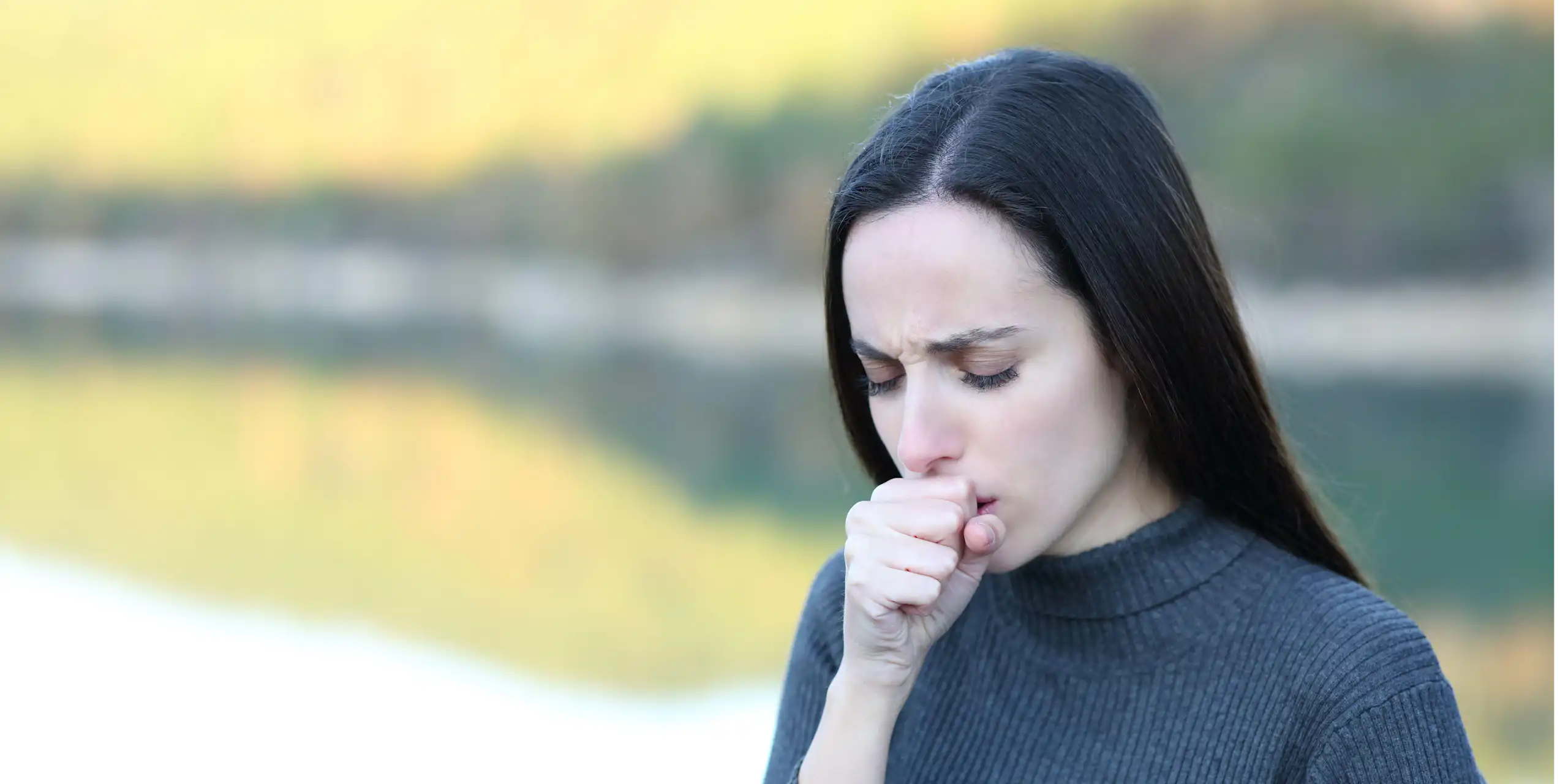 A woman coughing into her hand.