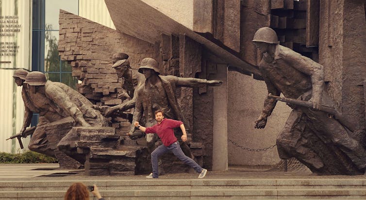Benji posing with a large sculpture of soldiers