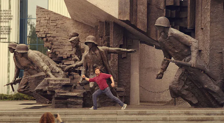 Benji posing with a large sculpture of soldiers