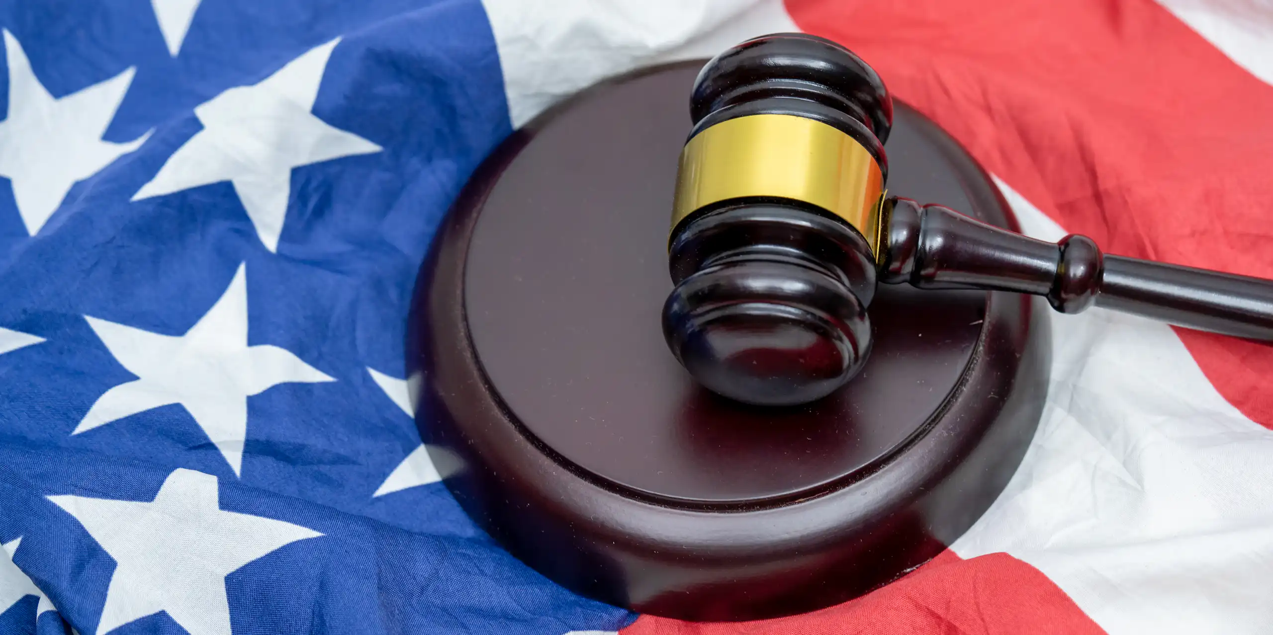 A judge's gavel and its striking pad on top of a US flag.