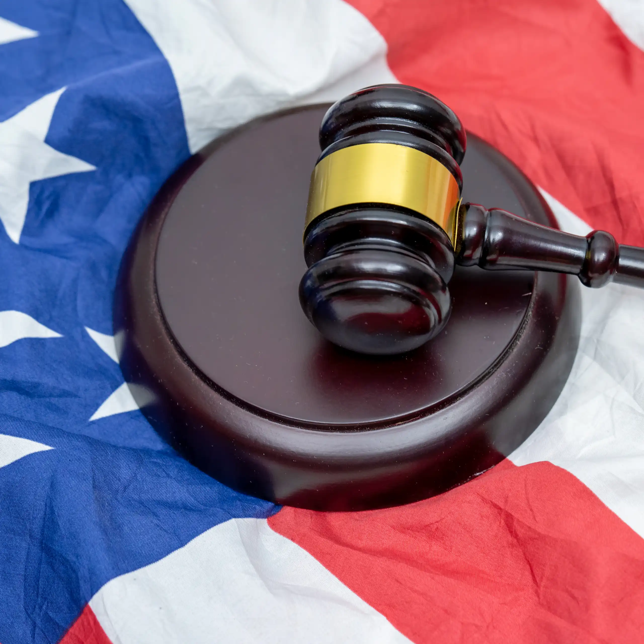A judge's gavel and its striking pad on top of a US flag.