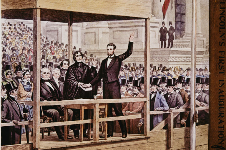 Two men in front of a crowd and under a scaffold, with one holding his hand on a book and the other hand waving in the air.