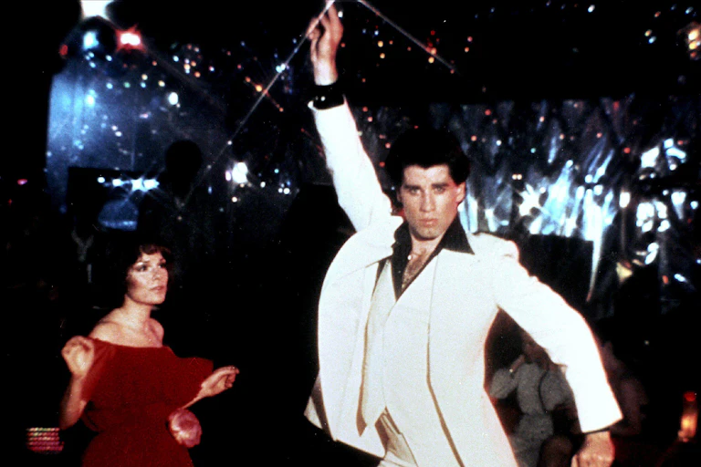 John Travolta in Saturday Night Fever, striking a pose in his white three-piece suit.