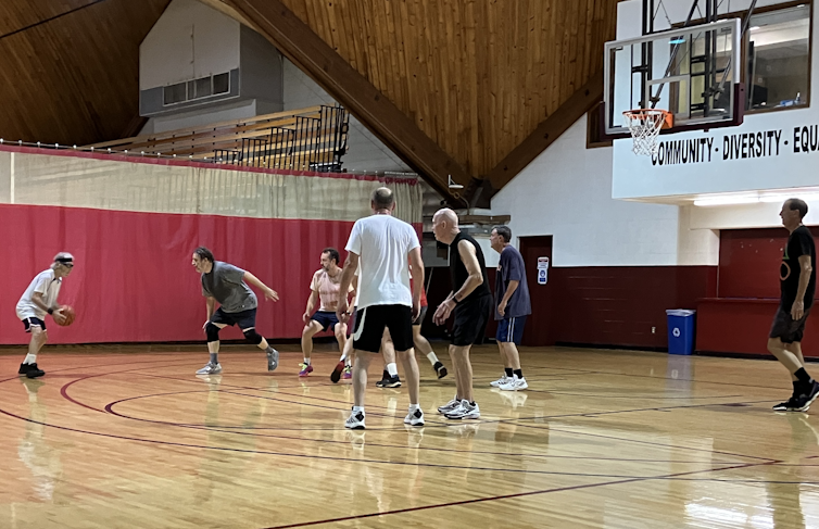 Several men play basketball in a gym.