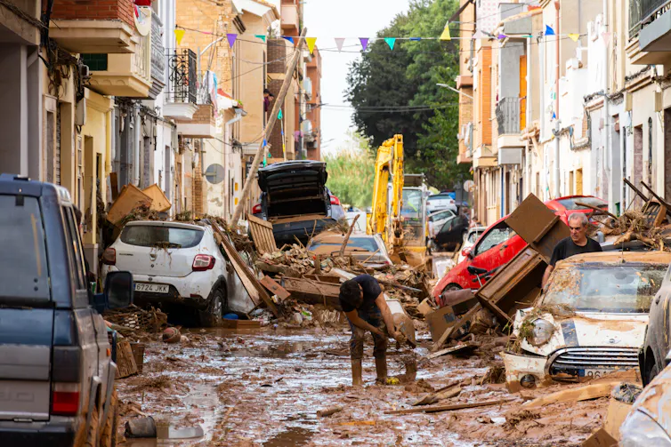 flooded street with damaged cars, broken houses, muddy water