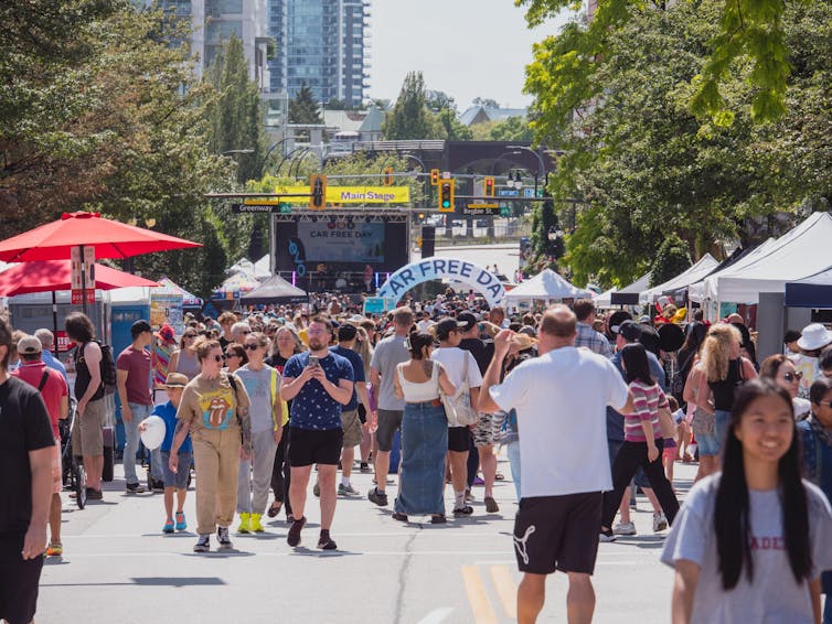 People stroll a city street on a sunny day.