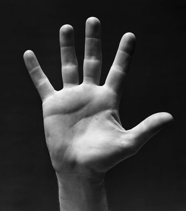 black and white photo of raised hand, palm to camera