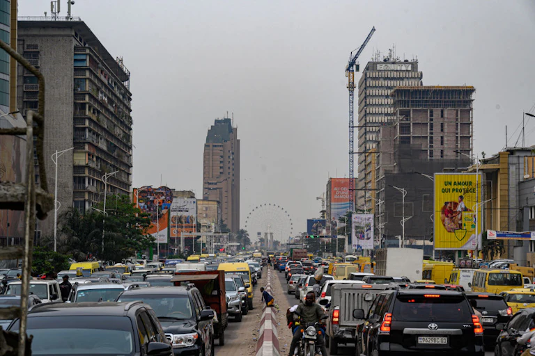 Cars lining up on both sides of a highway with high-rise buildings on either side of the streets