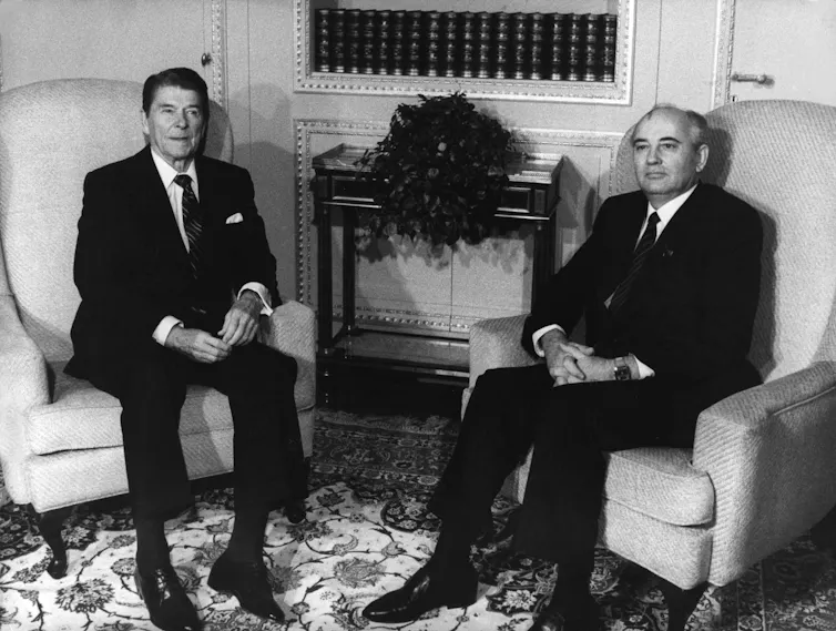 US president Ronald Reagan and Russian leader Mikhail Gorbachev sitting in armchairs.