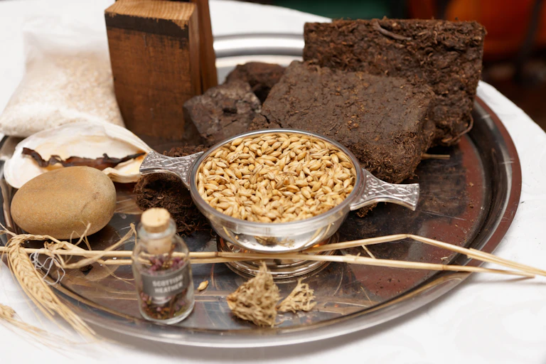 tray of whisky ingredients including black blocks of peat, oats etc