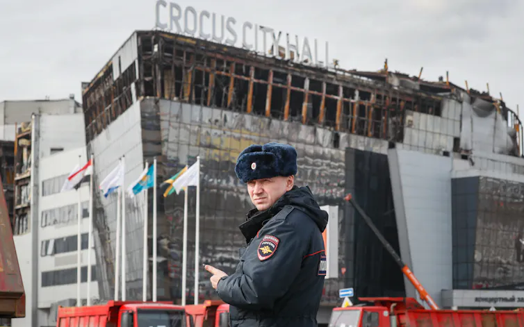 A police officer patrols in front of the burnt Crocus City Hall concert venue in Moscow.