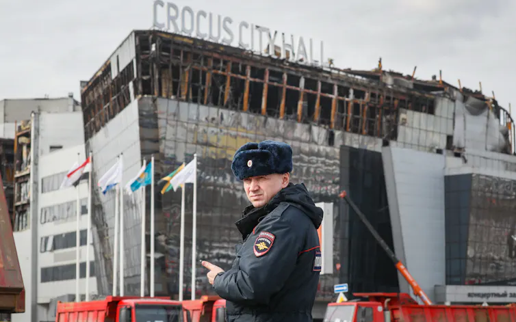 A police officer patrols in front of the burnt Crocus City Hall concert venue in Moscow.