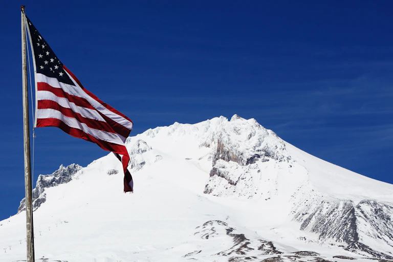 Un drapeau américain devant une montagne enneigée.