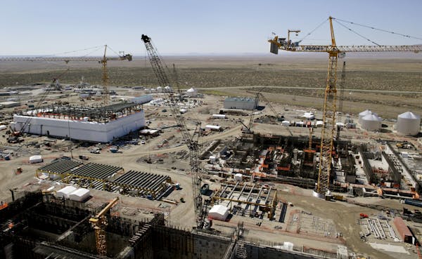 Cranes above a large industrial site with dusty shrubland in the background