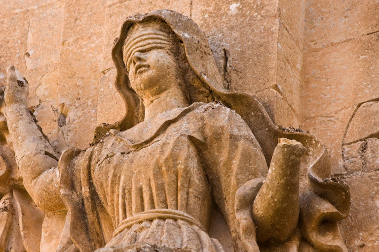 damaged stone relief of a blindfolded woman, missing a hand