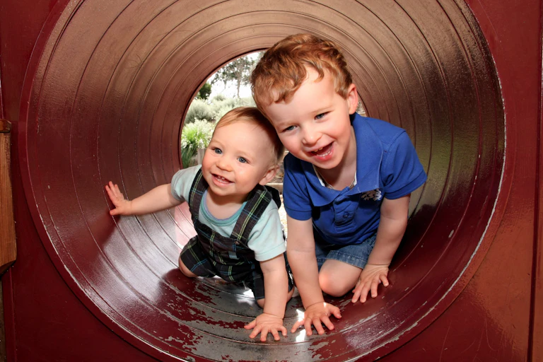 Two young children climbing through a tube