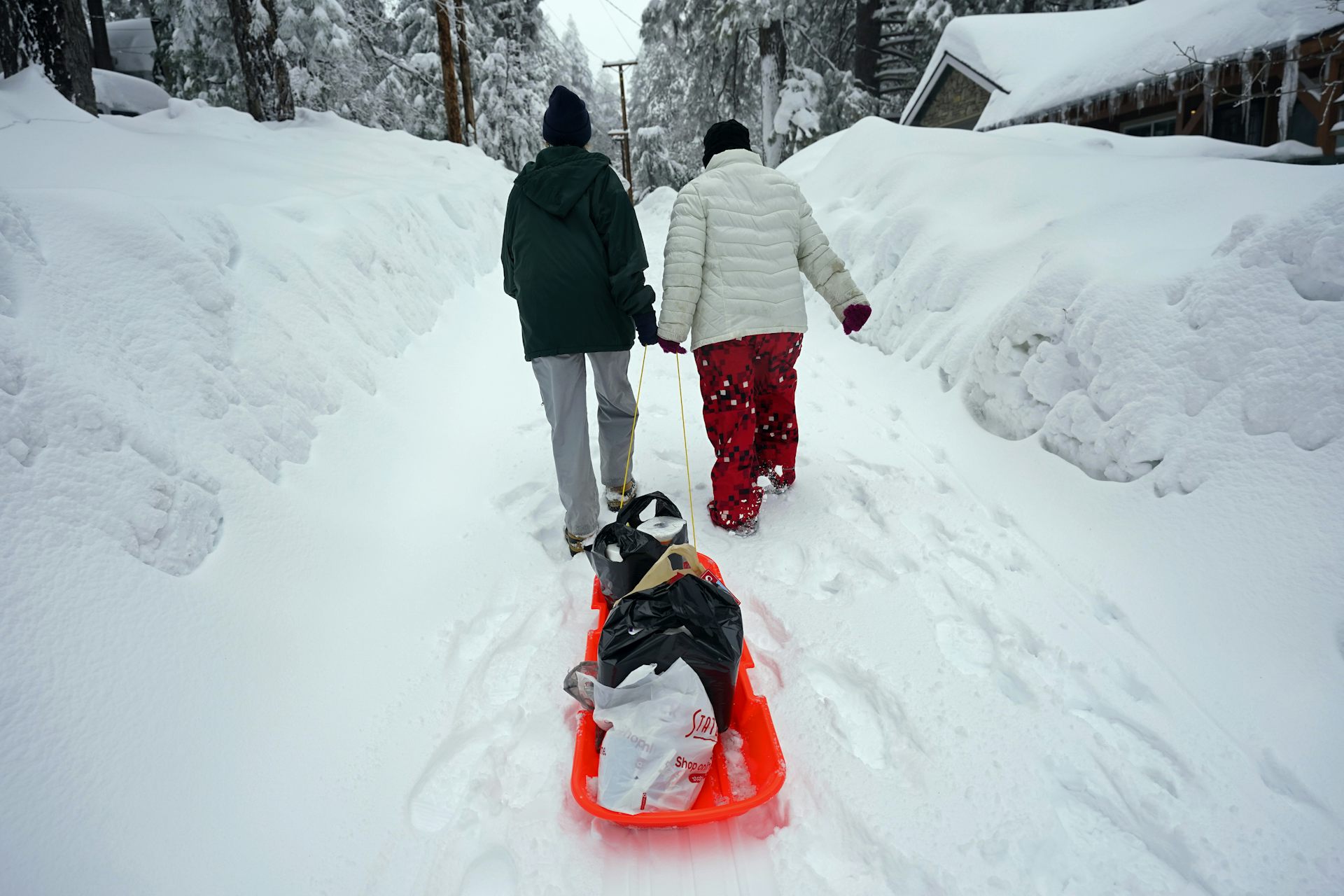 people drag sled through snow
