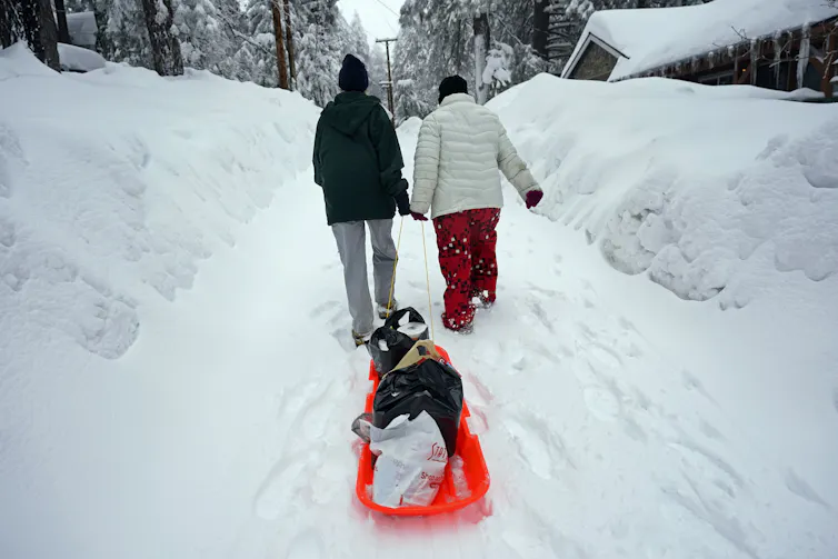 people drag sled through snow
