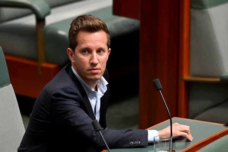 A man in a suit sits in the house of representatives