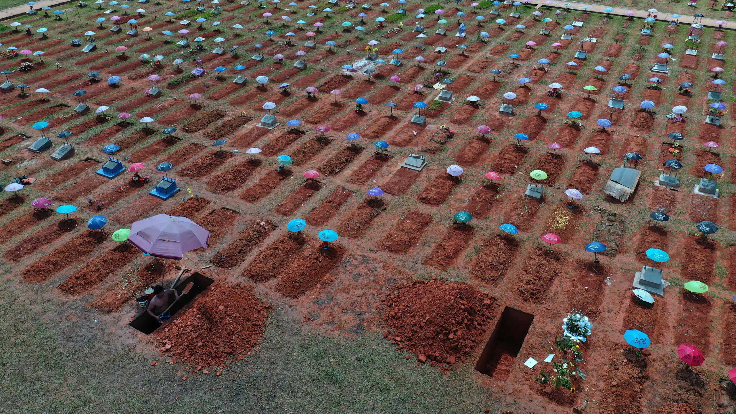 A wide shot of rows and rows of graves dug in fresh dirt.