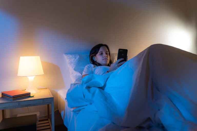 Young girl doomscrolling in bed.
