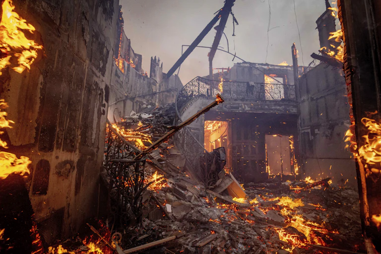A burning home, with the central staircase still standing.