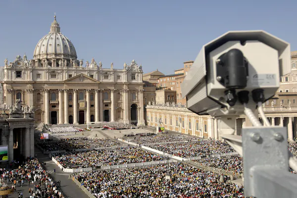 Surveillance camera overlooking a large crowd of people in front of a historical building.