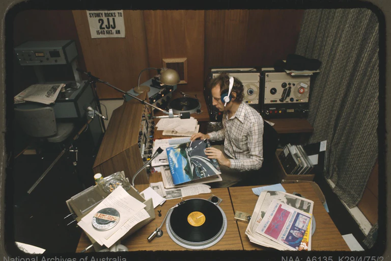 A man holds a record in a radio booth